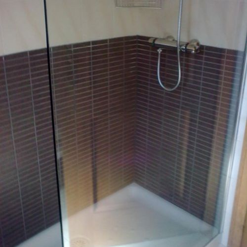 Sustitución de bañera por plato de ducha y colocación de azulejo tipo mosaico en tonos marrones